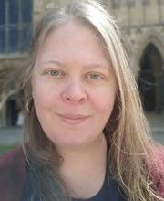 Dr. Kyla Bender-Baird with long straight dirty blonde hair wearing a black and maroon top