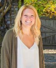 Dr. Amy Mercado smiling with long blonde hair wearing an open taupe sweater over a white v-neck blouse