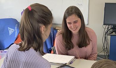  Adlai Greene works with a female student at a table.