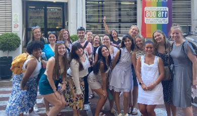 A group of people stand together to pose for photo with smiles on their faces 