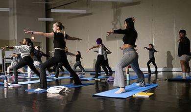 Students twist their bodies and extend their arms during a yoga exercise.