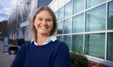 Woman stands smiling with arms crossed in front of her