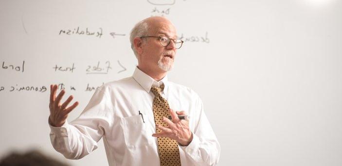 A professor teaching in front of a white board with words on it including Dark Ages, 都市生活, feudalism and lord.