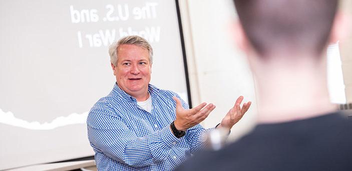 Professor Thomas Nester teaching American 军事 历史 sitting in front of a projector screen that says "The U.S. and World War I"