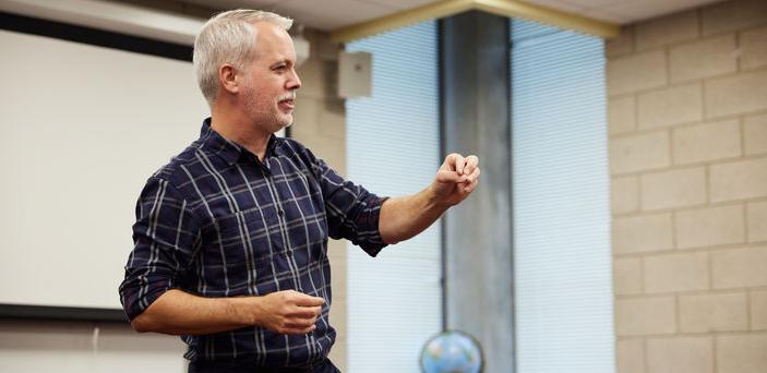 Dr. Matt Bell gestures as he teaches at the front of the class