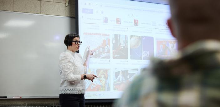 Dr. Melanie McNaughton points at images on a projector screen while teaching class